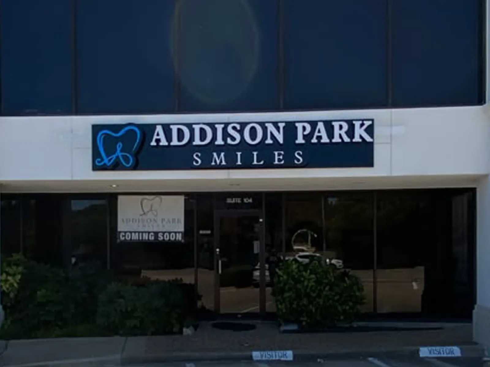 Addison Park Smiles cabinet sign with a blue tooth logo above a dental office storefront