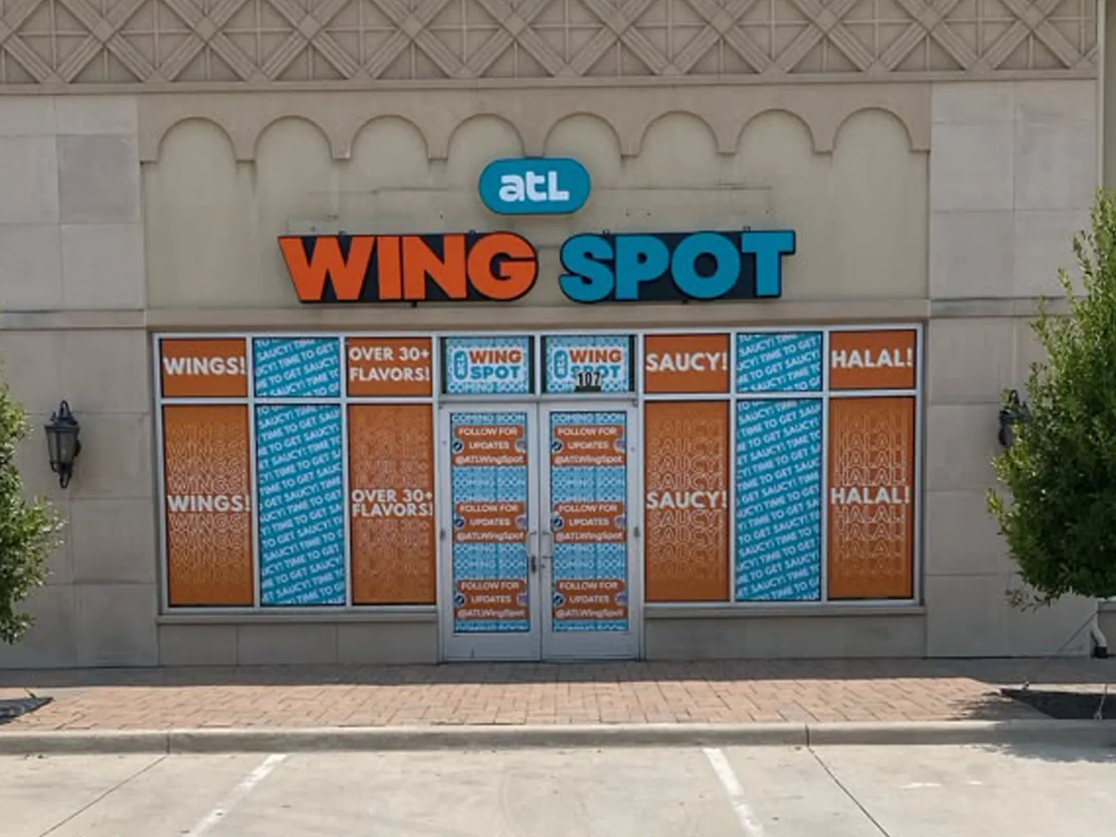 ATL Wing Spot orange and blue channel letters above storefront windows wrapped in matching graphics
