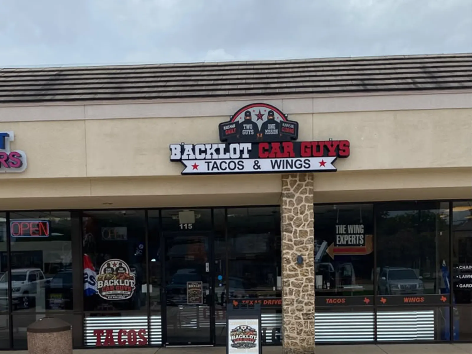 Backlot Car Guys Tacos and Wings sign with a round logo above a strip center restaurant