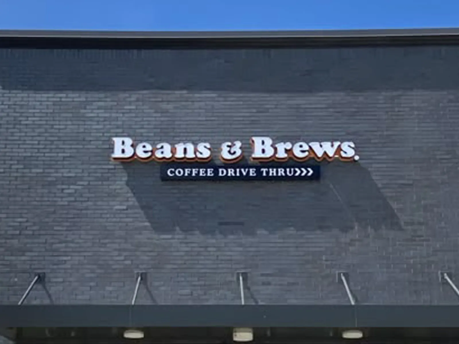 Beans and Brews Coffee Drive Thru dimensional letters on a dark painted brick wall