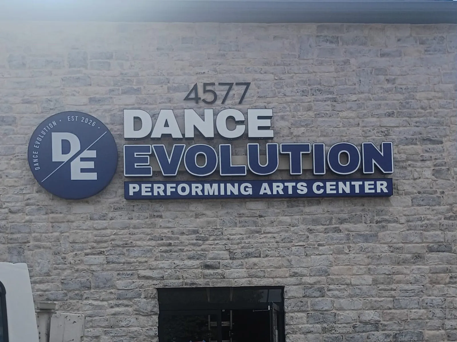 Dance Evolution Performing Arts Center logo, letters and address numbers on a stone facade