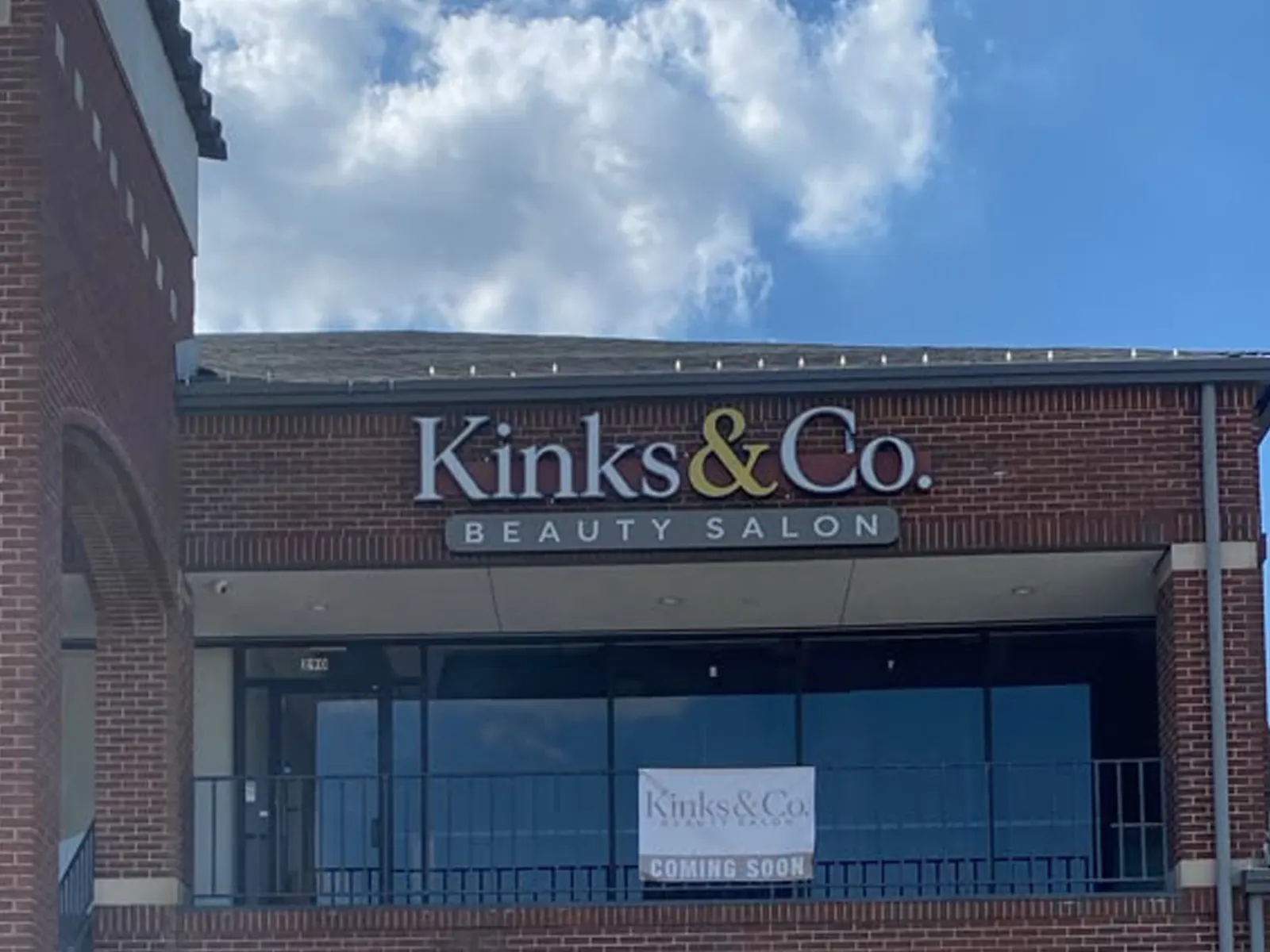 Kinks and Co. Beauty Salon letters on a panel above a brick storefront