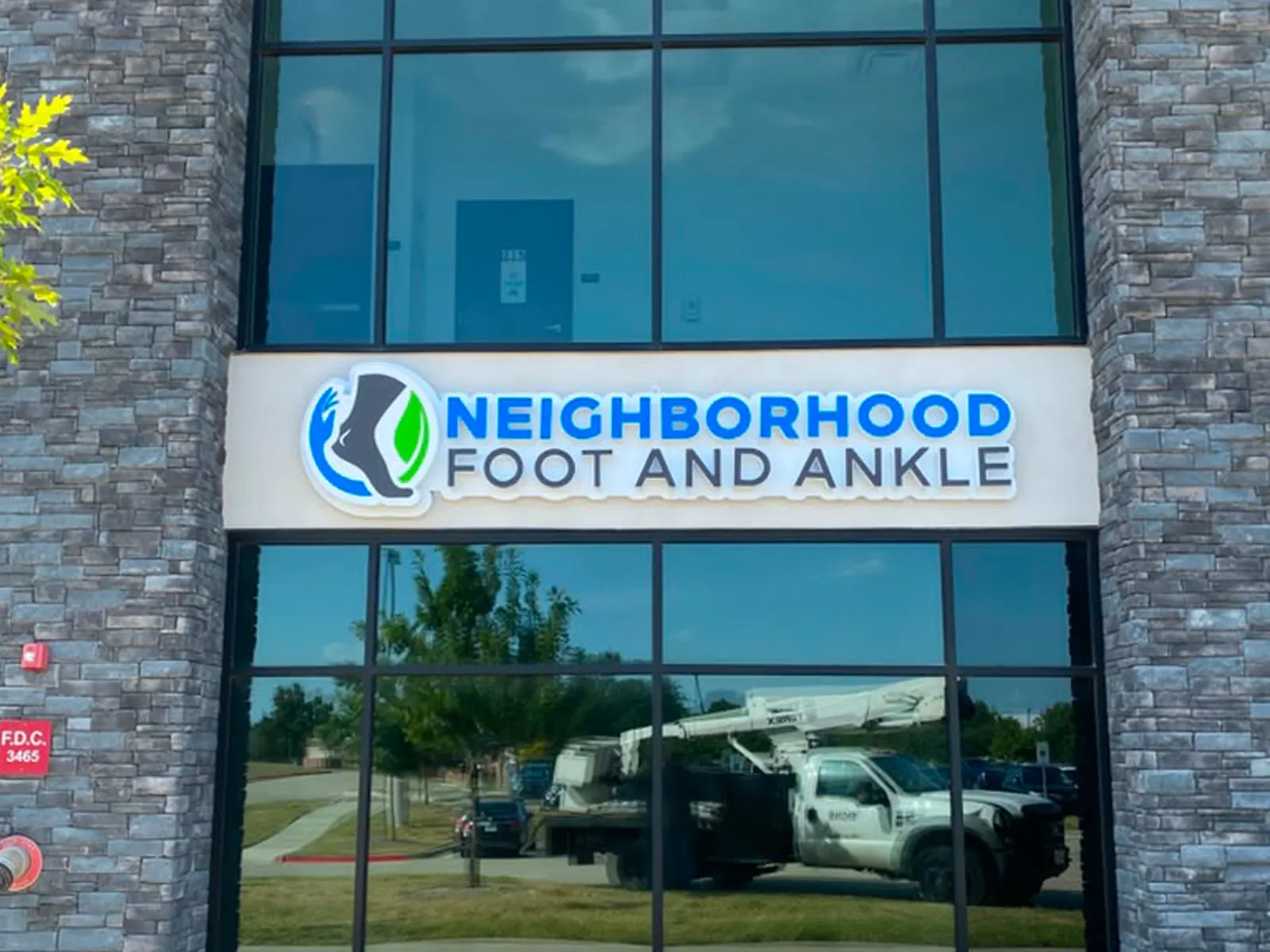 Neighborhood Foot and Ankle lit cabinet sign with a foot logo above a glass storefront