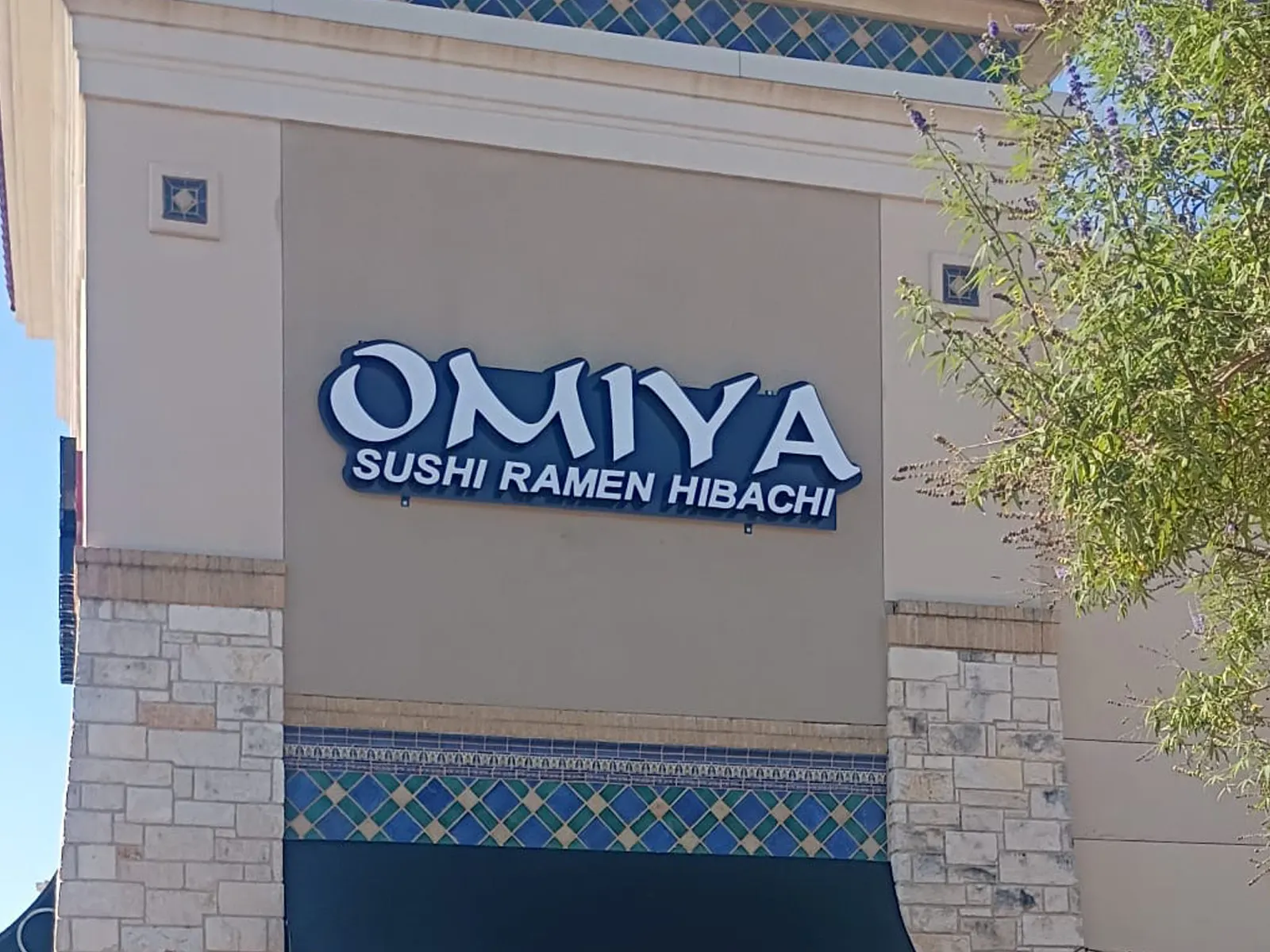 Omiya Sushi Ramen Hibachi blue channel letters on a stucco storefront tower