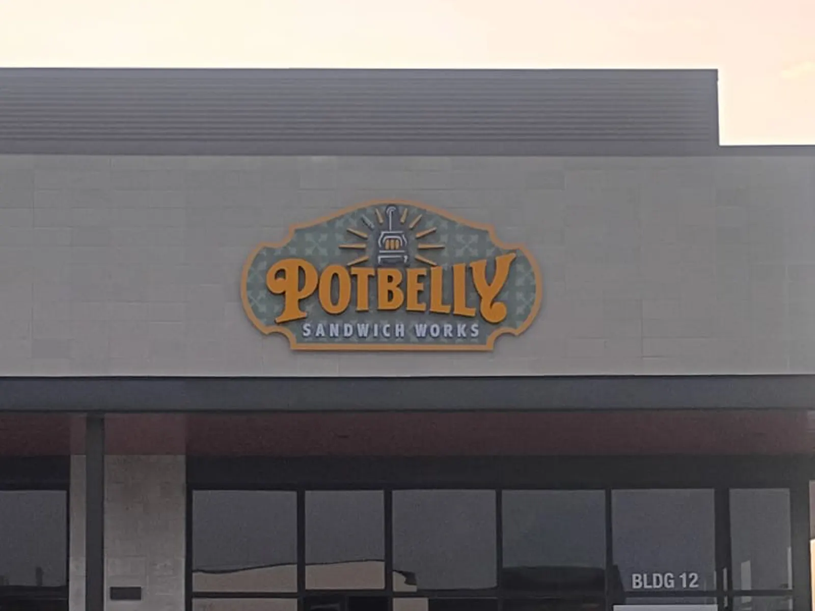 Potbelly Sandwich Works logo sign on a gray restaurant facade marked Bldg 12