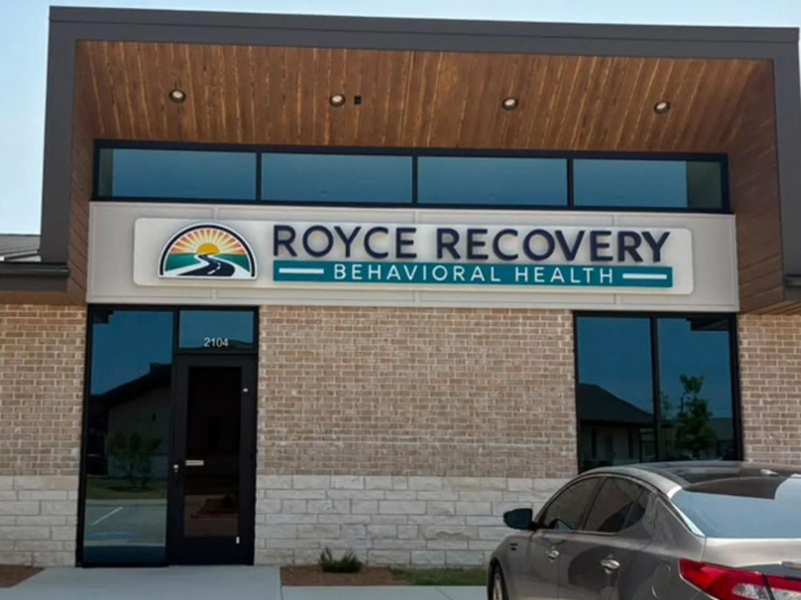 Royce Recovery Behavioral Health sign panel with a sunrise logo above a clinic entrance