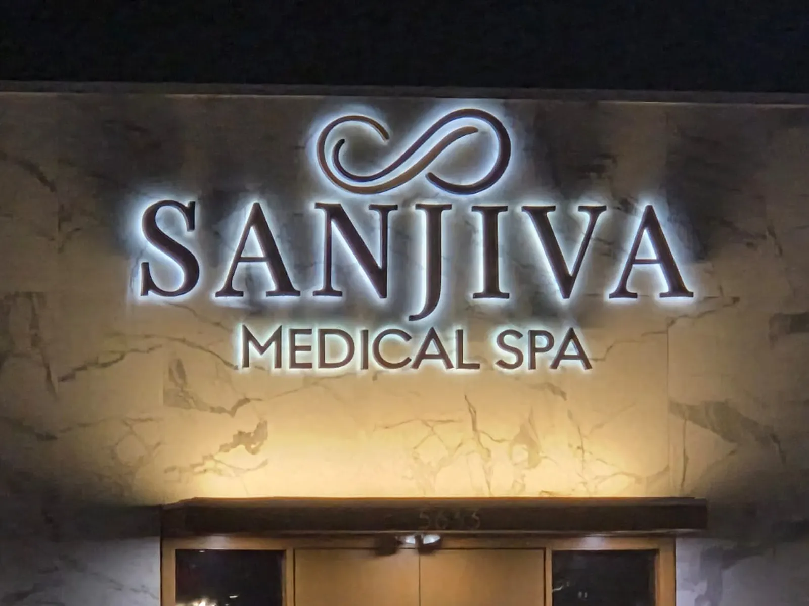 Sanjiva Medical Spa halo-lit letters and logo on a marble-look wall