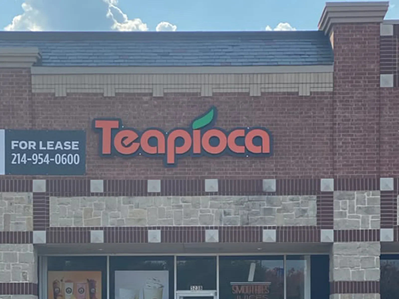 Teapioca red channel letters with a leaf accent on a brick and stone storefront