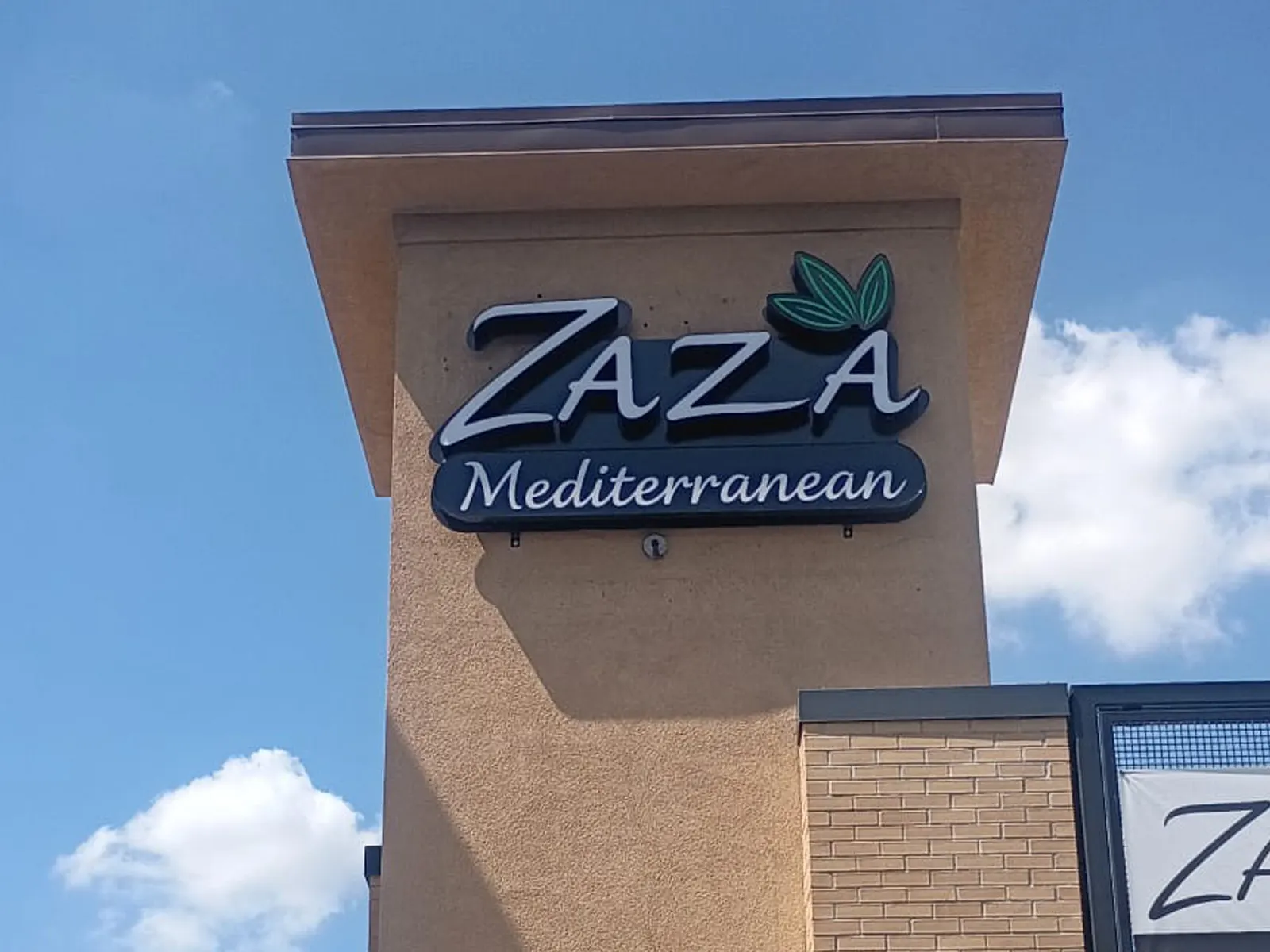 Zaza Mediterranean letters with a green leaf accent on a stucco tower