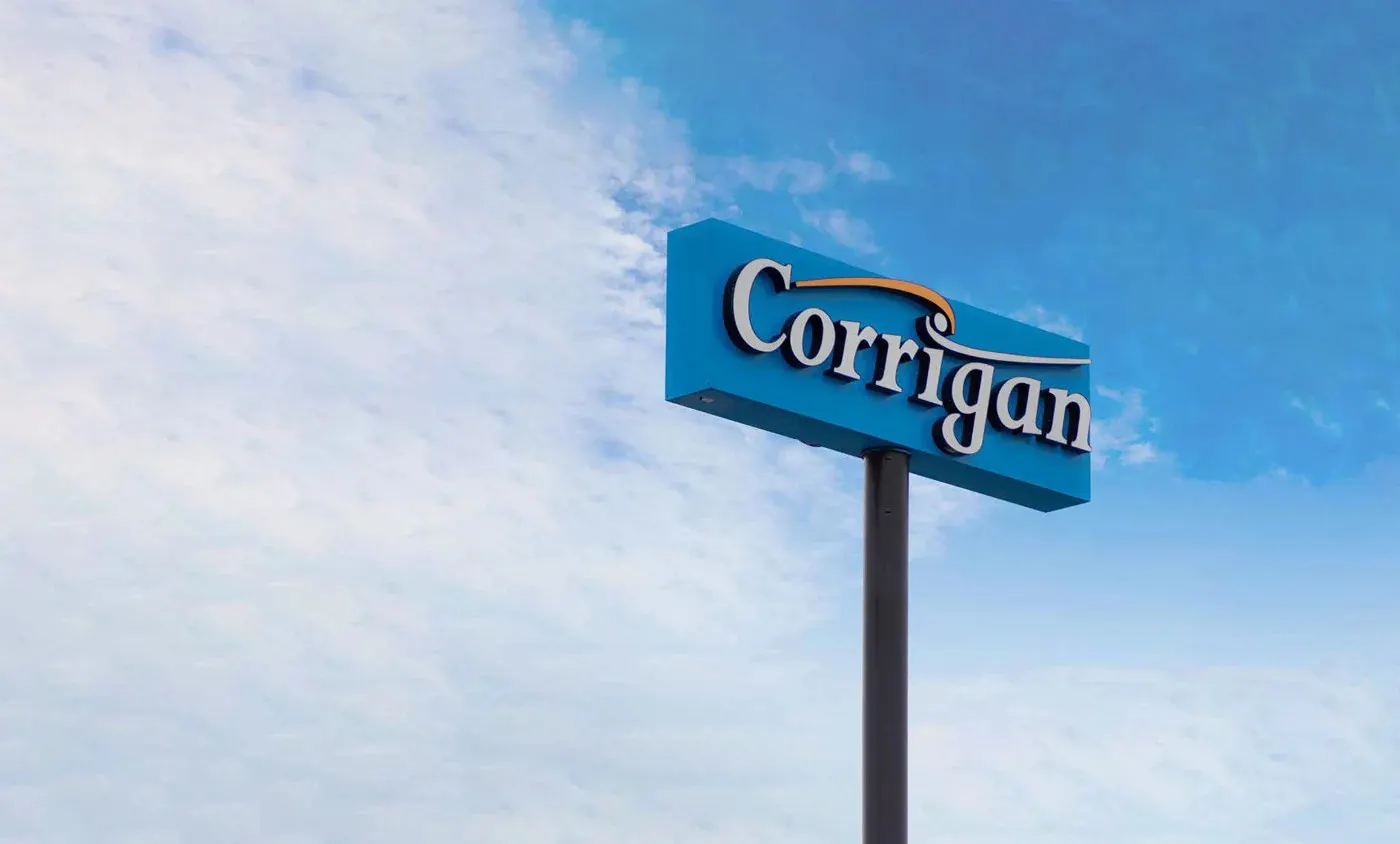 Corrigan pole sign with a blue cabinet on a single steel post against the sky