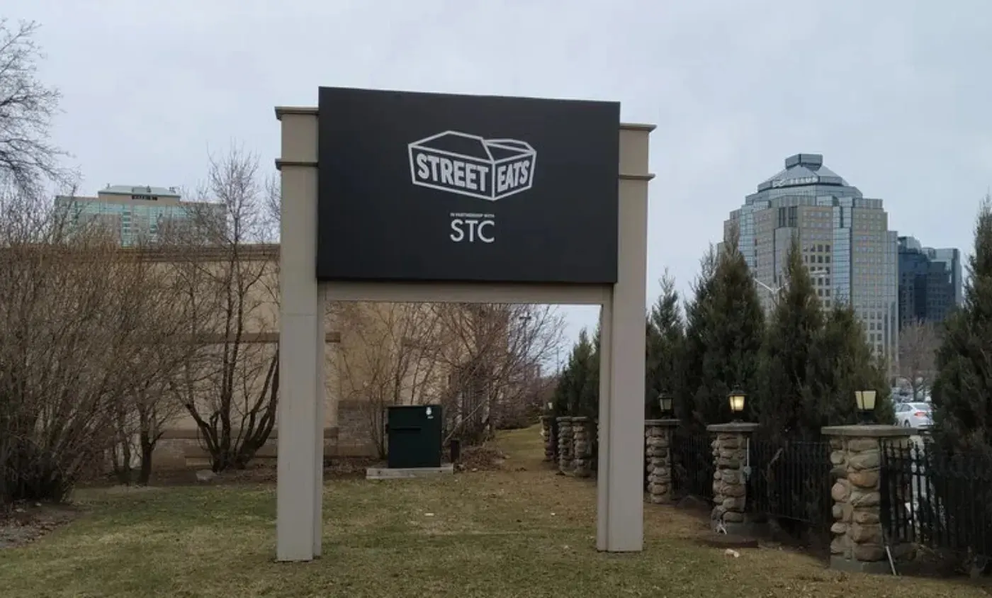 Street Eats STC sign panel framed between two posts at a property entrance